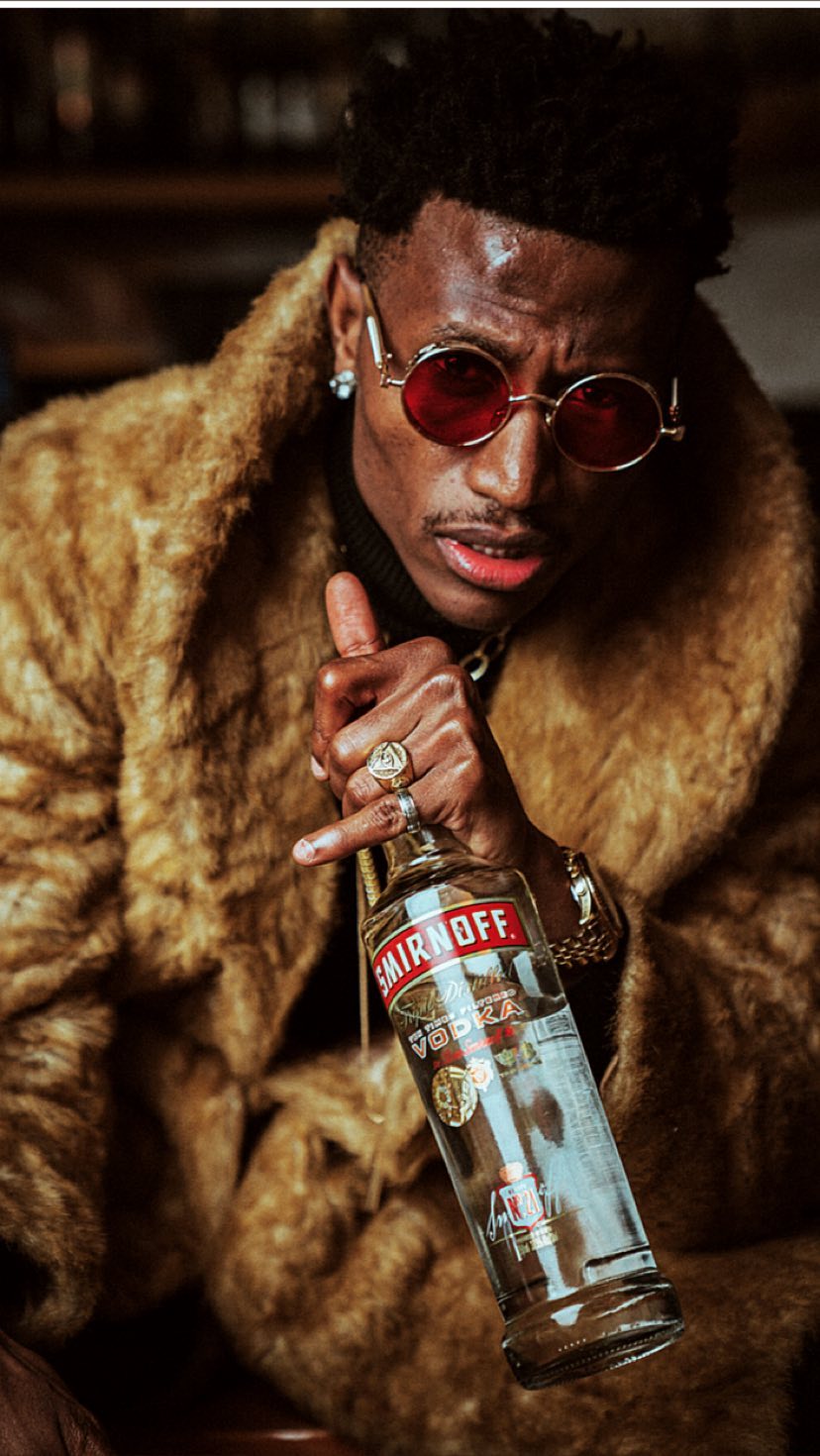 Octopizzo photo shoot as the new face of Smirnoff Kenya posing with a bottle of Smirnoff. photo credit: Instagram/octopizzo