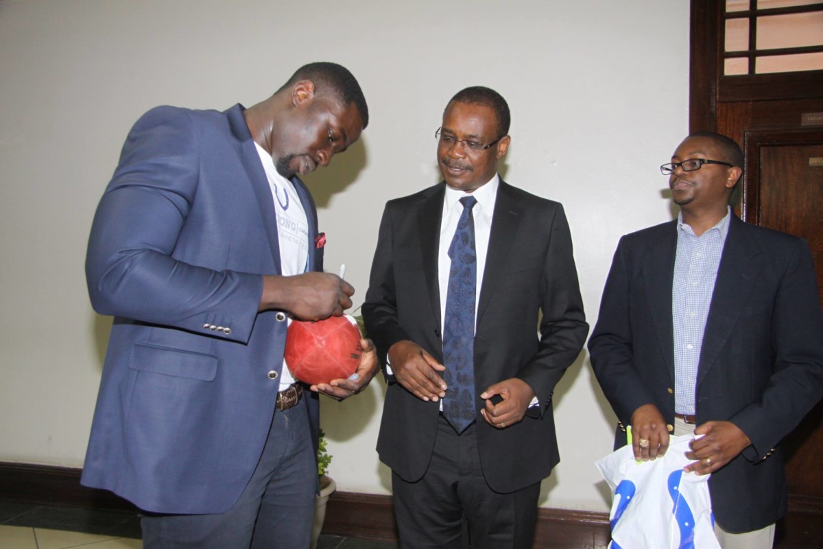 Daniel Adongo signing and handing over a football to the first Governor of Nairobi County Governor Evans Kidero in February 2014