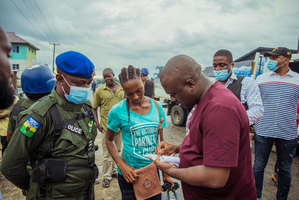 Marksman Chinedu Ijiomah writing a 500,000 Naira check to the stranger woman who was splashed water by one of his car fleet. Photo credit: Facebook/Marksman Chinedu Ijiomah