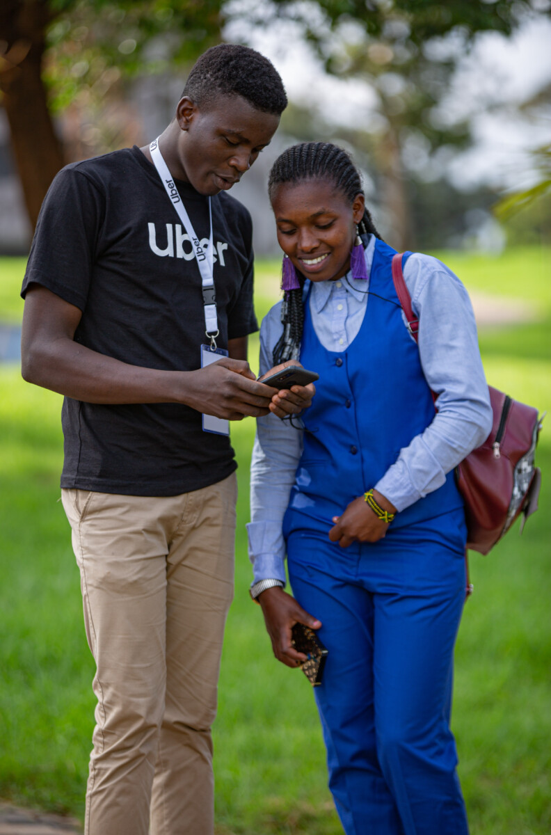 (L-R)Elosy Kathure is shown how to use the festival promo code by Uber brand ambassador Mourice Wankulu.